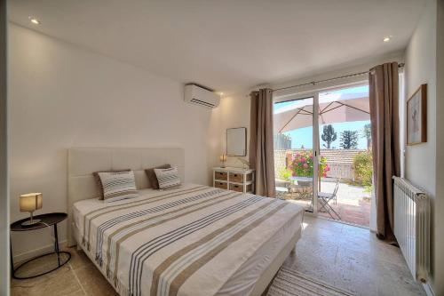une chambre blanche avec un lit et un balcon dans l'établissement Kathleen CANNES-GOLFE JUAN, à Vallauris