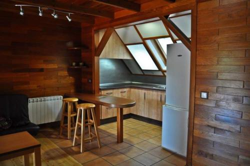 a kitchen with a refrigerator and a table with stools at Camping Caravaning Cuenca in Cuenca