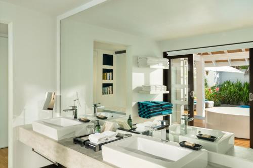a white bathroom with two sinks and a tub at Velassaru Maldives in South Male Atoll