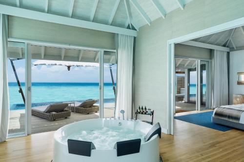 a master bathroom with a tub and a view of the ocean at Velassaru Maldives in South Male Atoll