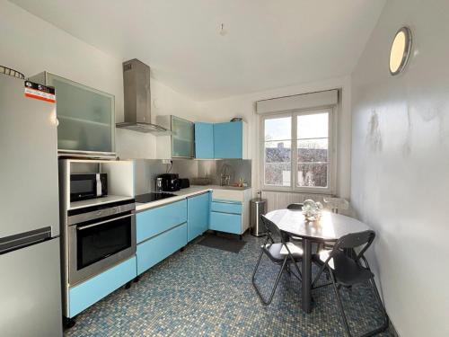 d'une cuisine avec des placards bleus et une table. dans l'établissement Le bonheur est dans le perche, à Saint-Jouin-de-Blavou