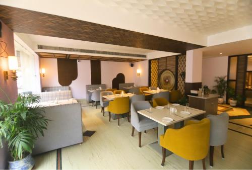 a dining room with tables and yellow chairs at Hotel Vasundhara Palace in Rishīkesh