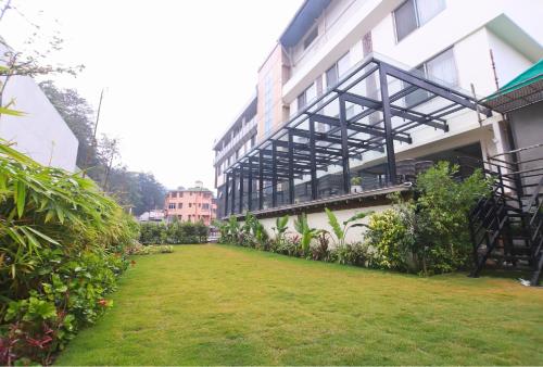 a building with a grass yard in front of it at Hotel Vasundhara Palace in Rishīkesh