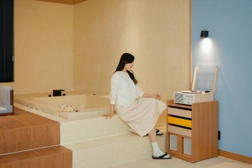 a woman sitting in a bath tub in a room at Aank Ryokan x Aank Air Cheongju in Cheongju