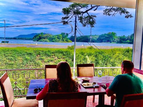 a man and woman sitting at a table looking out at the water at Tissa Yala Lake View Hotel in Tissamaharama