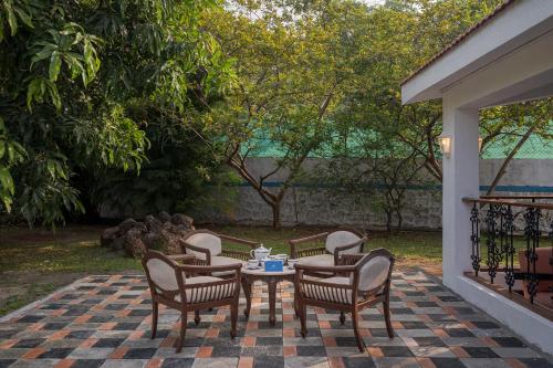 a patio with a table and chairs on a patio at SaffronStays Adora Woods & Hills, Luxury Pool Villa in Murud in Jambrung 