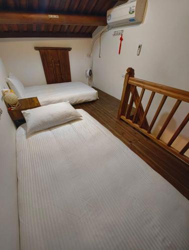 two beds in a room with a stair case at 湖峰古厝民宿 in Jinning