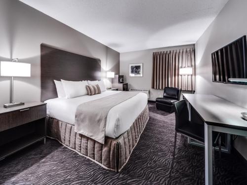 a hotel room with a large bed and a desk at Heritage Inn Hotel & Convention Centre - High River in High River