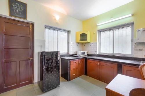 a kitchen with wooden cabinets and a black refrigerator at Casa De Fazenda - Farmhouse, Diwar Island in Divar
