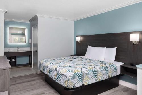 a hotel room with a bed and a bathroom at Travelodge by Wyndham Lemoore Near Naval Air Station in Lemoore