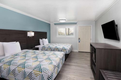 a hotel room with two beds and a flat screen tv at Travelodge by Wyndham Lemoore Near Naval Air Station in Lemoore