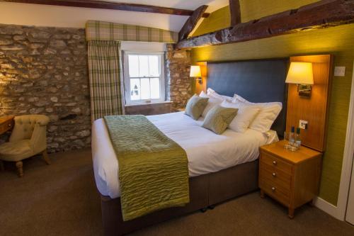 1 dormitorio con 1 cama grande y pared de piedra en Sun Inn en Kirkby Lonsdale