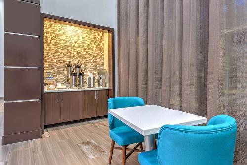 a dining room with a table and two blue chairs at La Quinta by Wyndham Tyler - University Area in Tyler