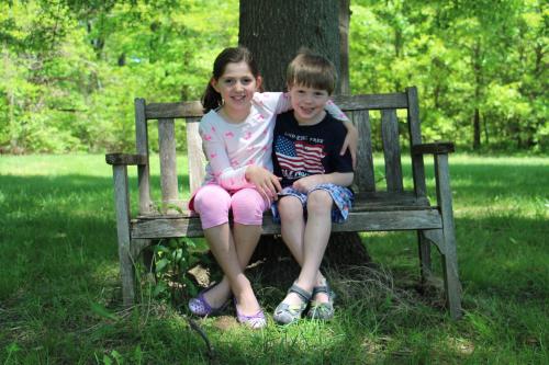 a boy and a girl sitting on a bench next to a tree at Cedar Creek in New Haven