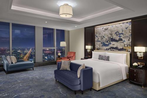 a bedroom with a bed and a couch and a chair at Waldorf Astoria Chengdu in Chengdu