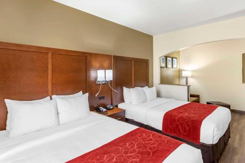 a hotel room with two beds with red sheets at Comfort Suites Ogden Conference Center in Ogden