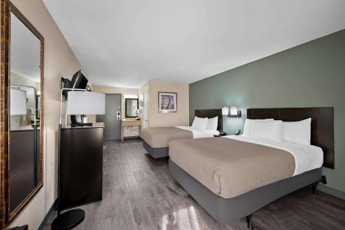 a hotel room with two beds and a mirror at Quality Inn Fort Myers Cape Coral in Fort Myers