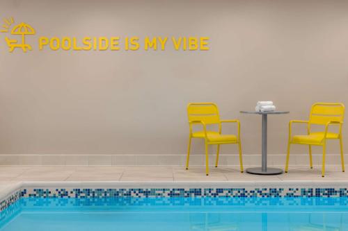 a pool with two yellow chairs and a table and chairs next to a table at Home2 Suites By Hilton Virginia Beach Princess Anne in Virginia Beach