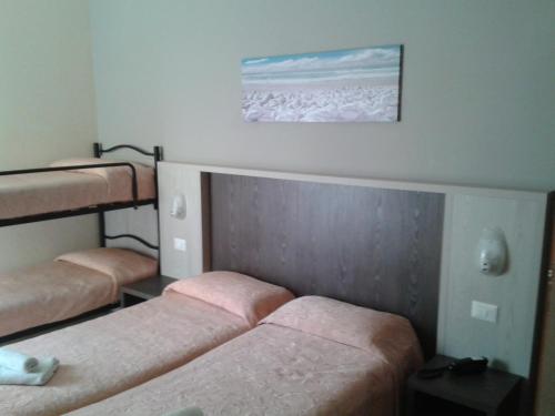 a room with three beds and a painting on the wall at Hotel Senyor in Rimini