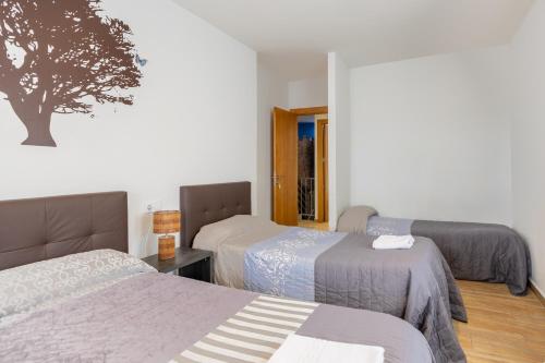 ein Schlafzimmer mit zwei Betten und einem Baum an der Wand in der Unterkunft Casa Rural Camino De Avila in Mediana de Voltoya