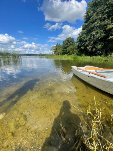 a shadow of a person in the water next to a boat at Stodoła nad wodą in Olecko Małe