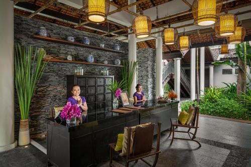two people sitting at a counter in a room with plants at Anantara Lawana Koh Samui Resort in Chaweng