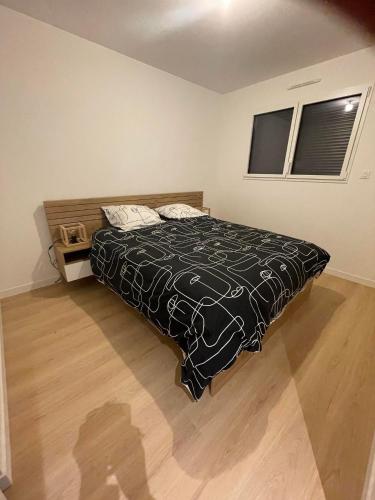 une chambre avec un lit avec une couette noire et blanche dans l'établissement Maison neuve mer, plage, gr 34 à pieds, à Assérac