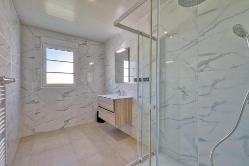 une salle de bain avec une douche en verre et un lavabo dans l'établissement Maison Corail 1 - Climatisation jardin et parking, à Saint-Pierre-dʼOléron