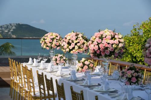 a long table with flowers in vases on it at Anantara Lawana Koh Samui Resort in Chaweng