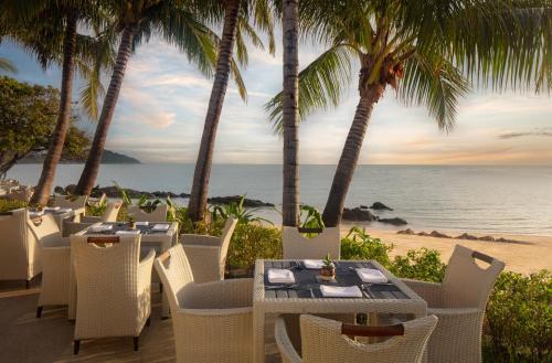 a restaurant on the beach with palm trees and the ocean at Anantara Lawana Koh Samui Resort in Chaweng