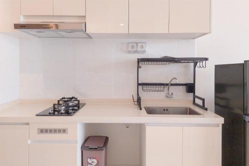 a kitchen with white cabinets and a sink at Good Choice and Comfy 2BR Sky House BSD Apartment By Travelio in Tangerang