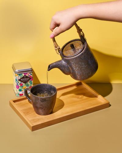 a person pouring coffee into a cup on a wooden tray at Anantara Lawana Koh Samui Resort in Chaweng