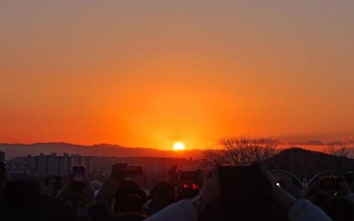 a crowd of people taking pictures of the sunset at House of Gallery Hyomok in Daegu