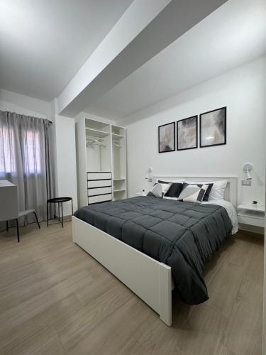 a white bedroom with a large bed and a desk at HilMar Holiday Home in SantʼAgata di Militello