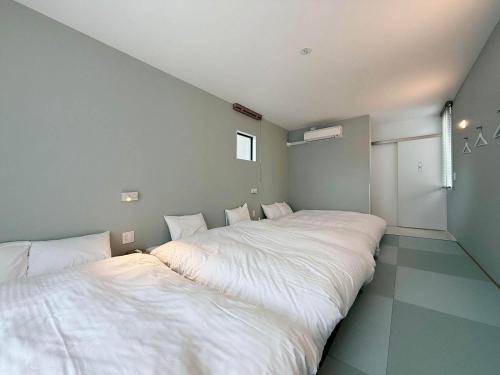two beds in a room with white sheets at MitO Onomichi - Sauna & Scenic 3-Story Stay in Kaneyoshi