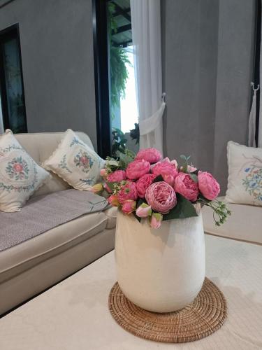 a white vase filled with pink flowers on a table at Baan norn nub dao pai in Pai