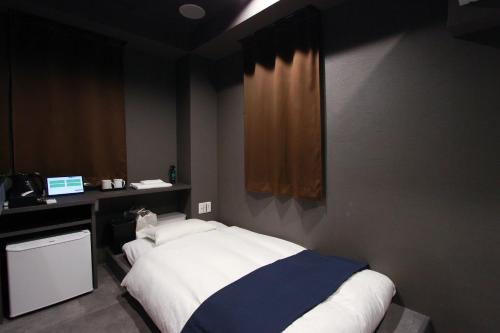 福岡市にあるEpoch inn Nakasuのベッドとパソコン付きの机がある寝室