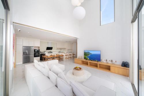 a living room with a white couch and a kitchen at Your Private Piece of Paradise! 4BR Pool Villa in the New Lux Pride 2 V9 Residence in Bang Tao Beach