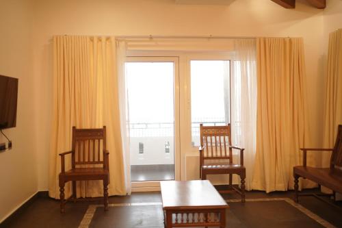 a living room with two chairs and a table and a window at Golden Sands Cherai in Cherai Beach