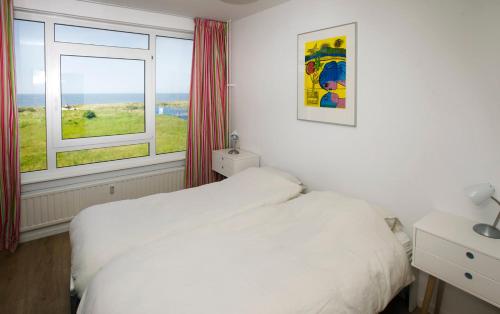 ein Schlafzimmer mit einem weißen Bett und einem Fenster in der Unterkunft bij Miep in Egmond aan Zee