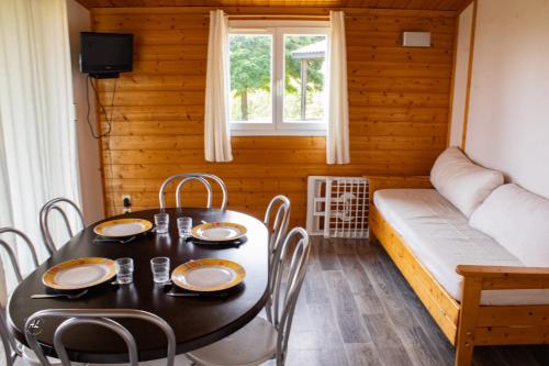 a dining room with a table and chairs and a couch at H des Lacs 3p 6pers in Monclar-de-Quercy