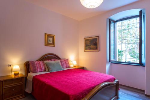 a bedroom with a bed with a pink blanket and a window at Casa Margherita PT, Borno Ospitar in Borno