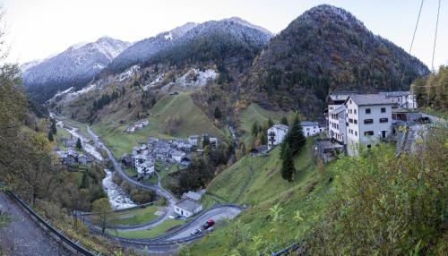 a village on a hill with a road and mountains at ALBERGO VALLUNGA in Tartano