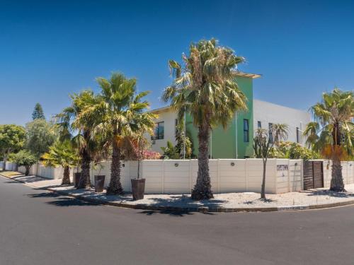 a house with palm trees in front of a street at Cape Town 4U Guesthouse in Cape Town