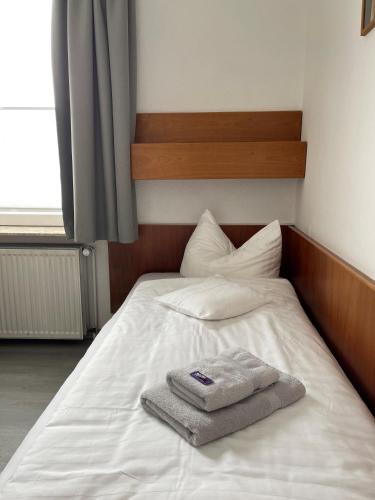 a white bed with a towel on top of it at Hotel Passat in Borkum