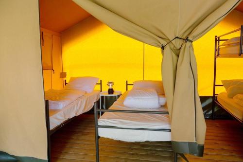 a room with two bunk beds and a yellow wall at Safari tent Heeg 4 persons in Heeg