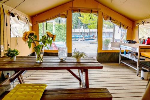 a room with a wooden table with flowers on it at Safari tent Heeg 4 persons in Heeg