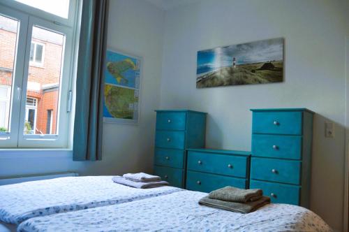 a bedroom with two beds and a dresser and a window at Villa Scherz - stilvoll, zentral, ruhig, EG in Borkum