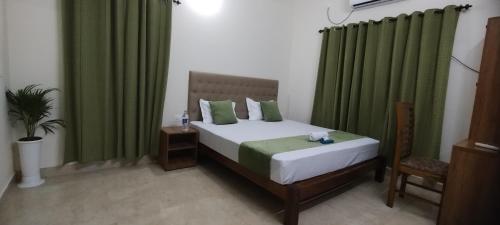 a bedroom with a bed with green curtains at Zora Rooms in Alleppey