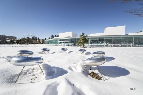 a group of chairs in the snow in front of a building at HOTEL AO Kanazawa in Kanazawa